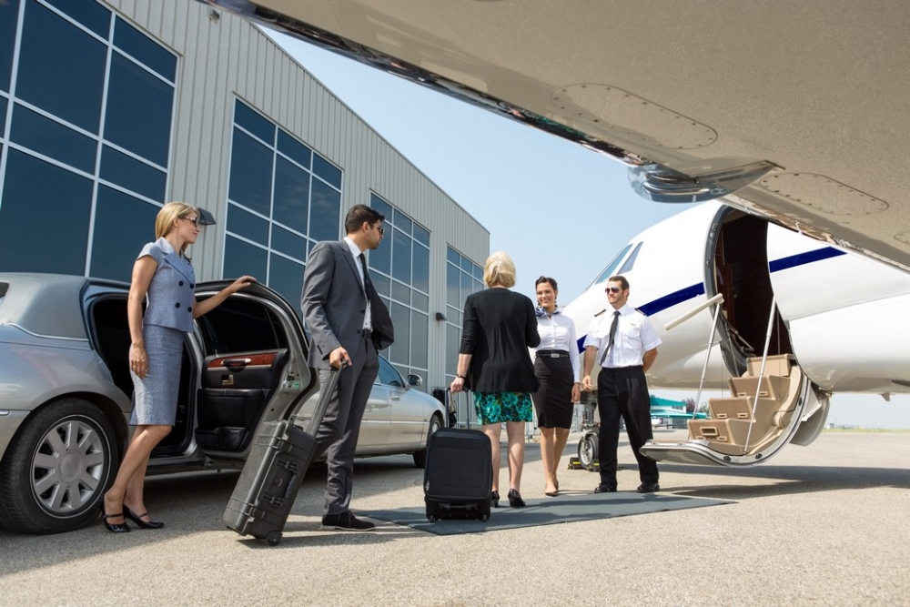Business professional about to board private jet while airhostess and pilot greeting them